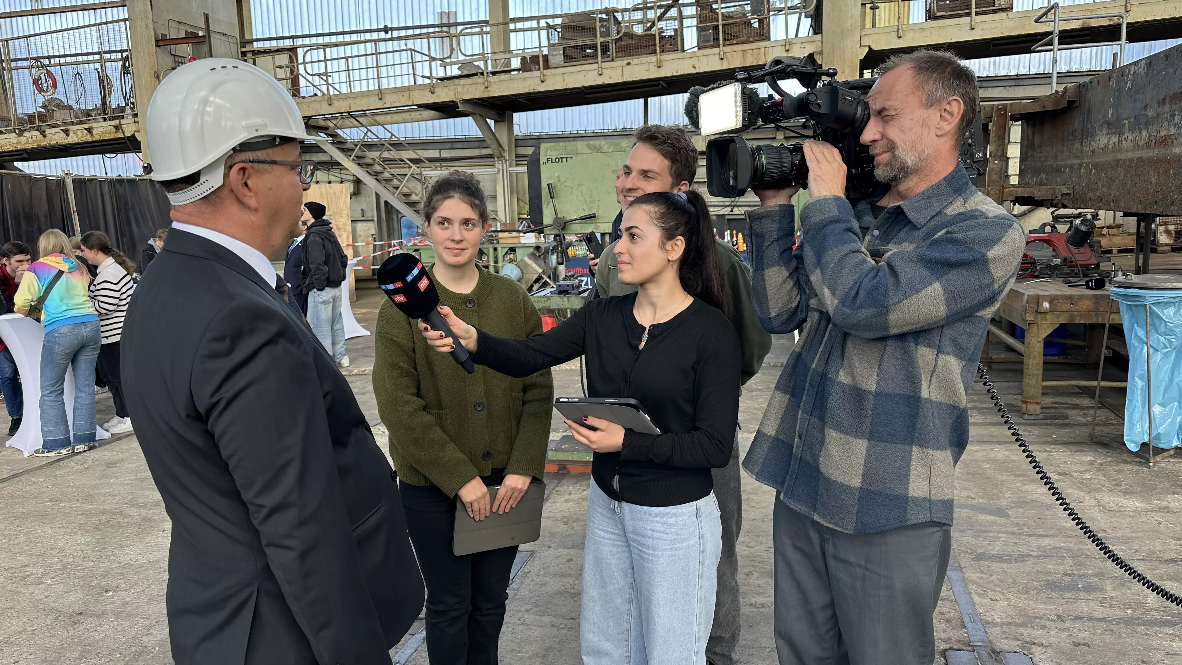 Schüler:innen interviewen jemanden mit einem Mikrofon, das Interview wird mit einer Fernsehkamera gefilmt